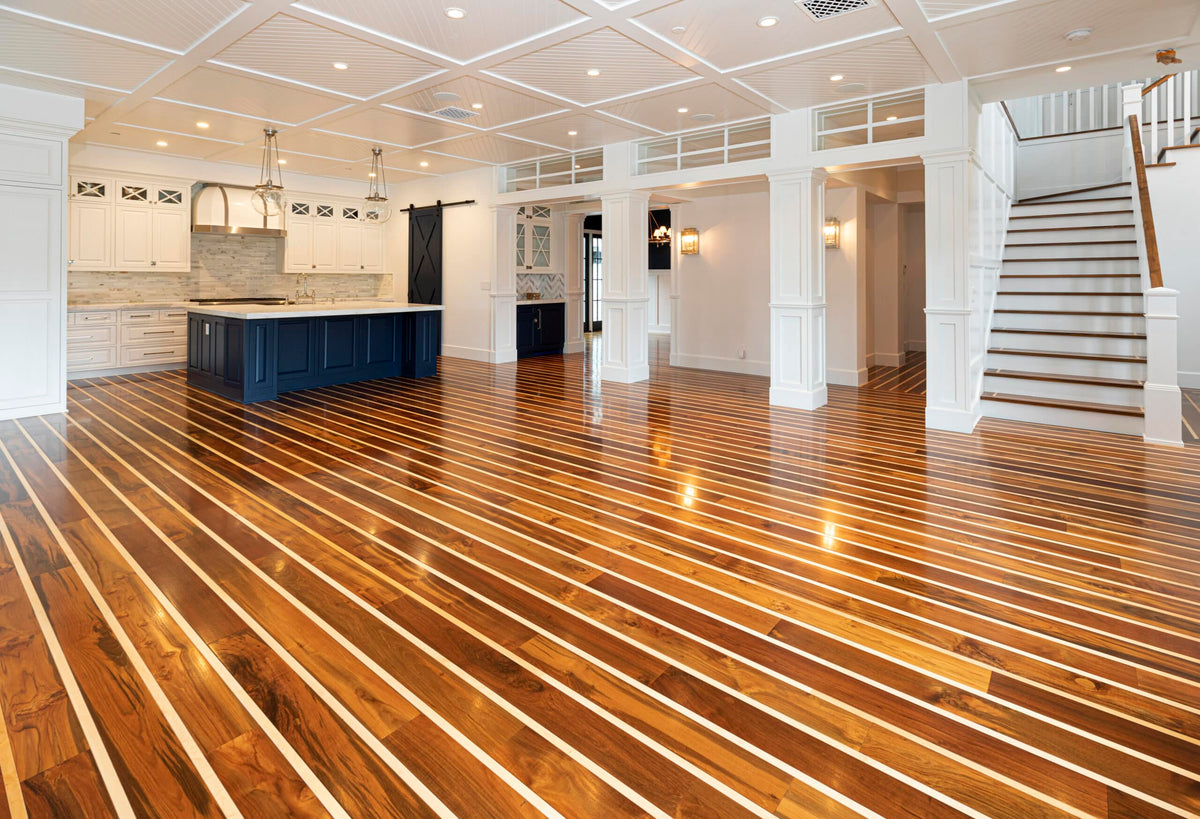 Striped wood flooring across an open-plan room with white walls, a navy kitchen island and a staircase
