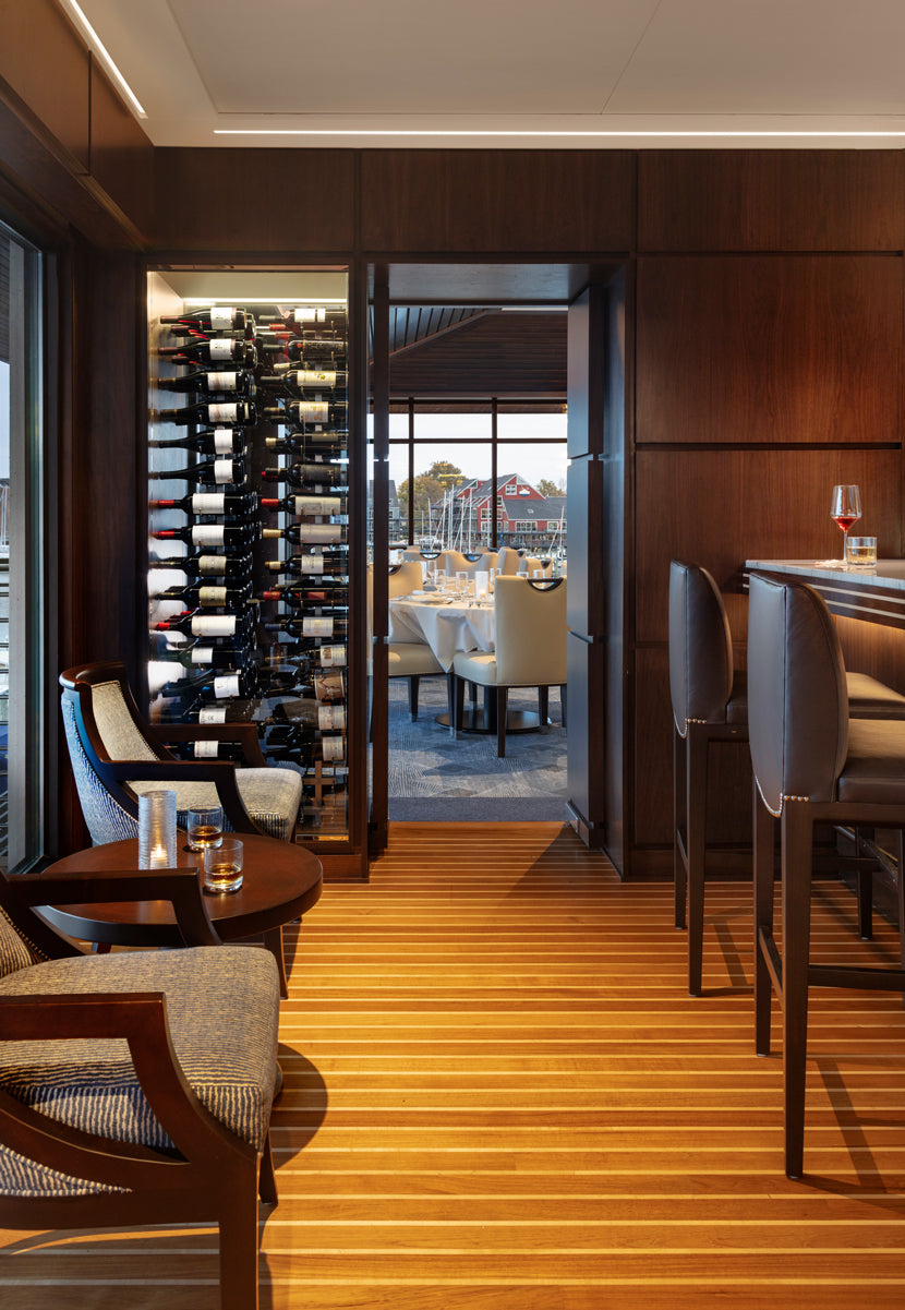Striped wood floor leads past dark wood cabinetry and seating to a glazed doorway