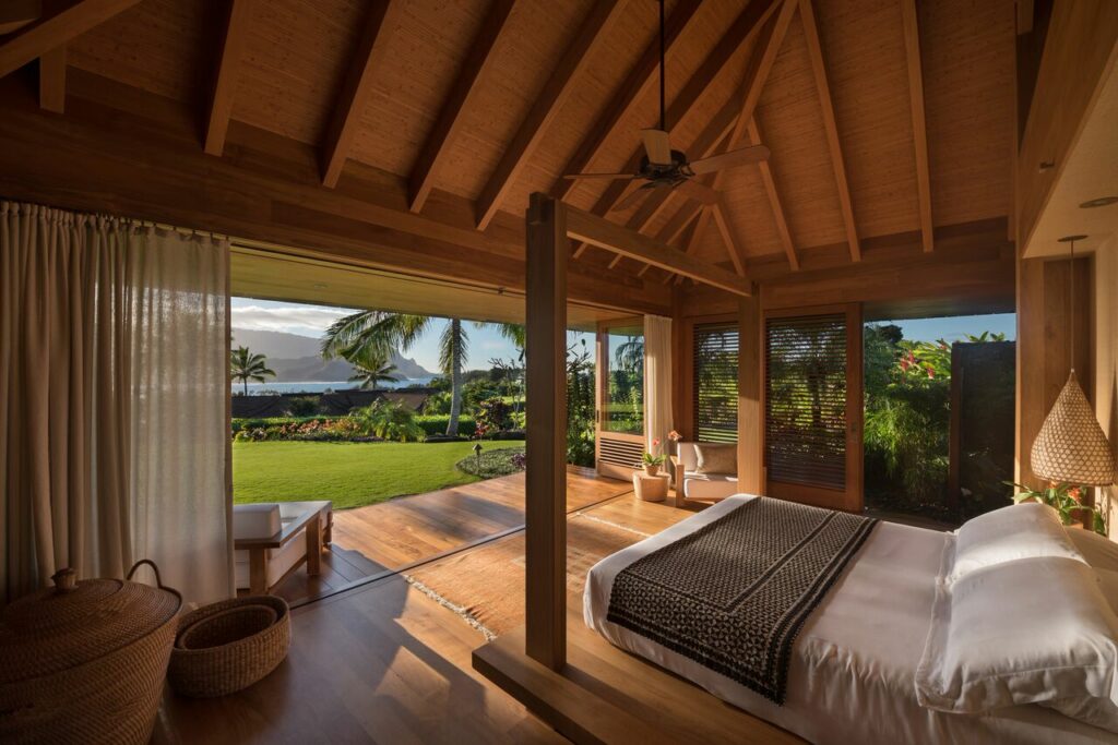 Sunlight across teak flooring in a bedroom with large openings and curtains