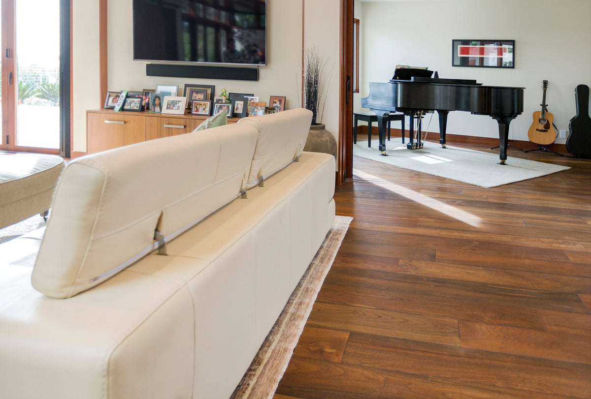 Living room from behind a pale sofa, with wood flooring and piano beyond