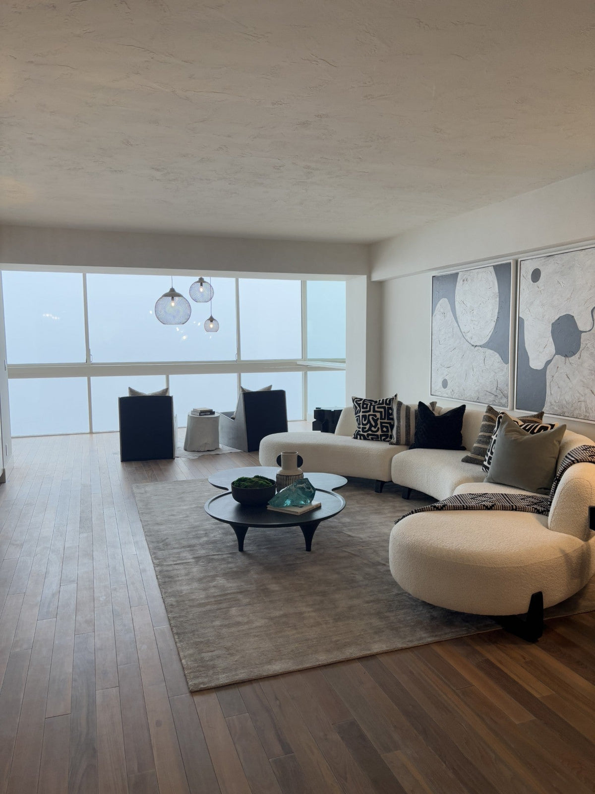 Modern living room with curved white sofa, rug, and pale wood flooring