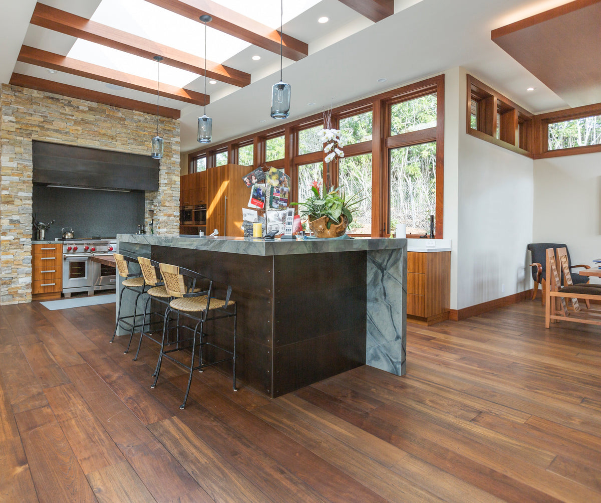Wide kitchen view with dark stone island, exposed timber, and varied wood floor