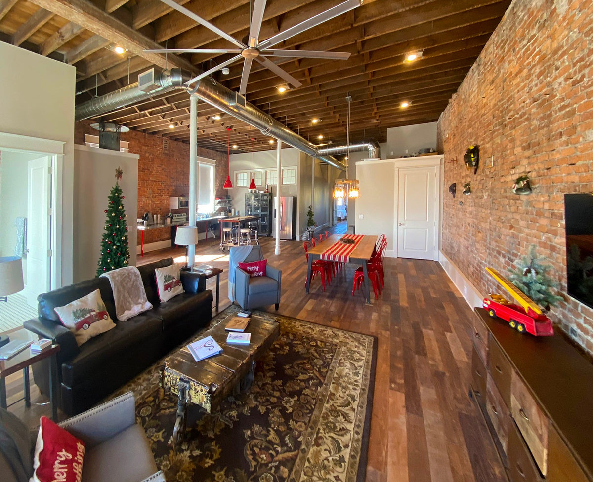 Loft living area with varied wood flooring, patterned rug, and exposed brick