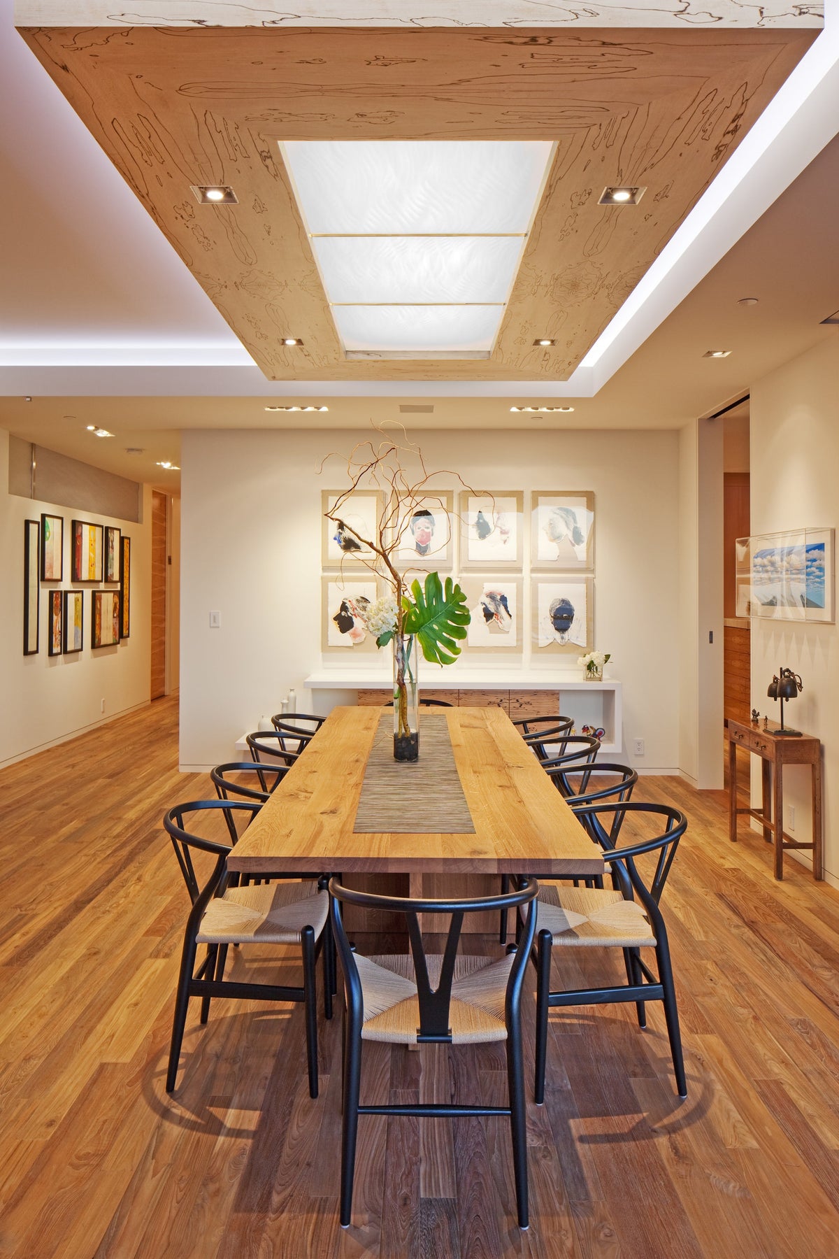 Dining room with long wood table, dark chairs, and wood plank floor