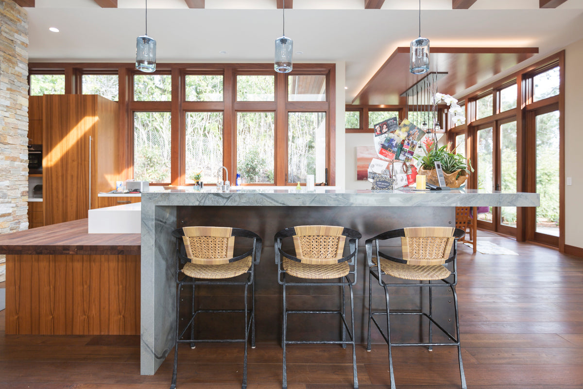 Kitchen island with dark stone and wood cabinetry above brown plank flooring