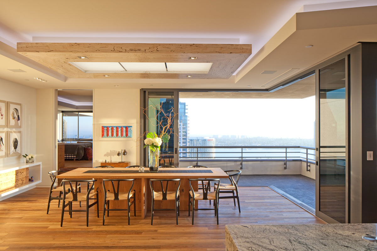 Broad dining room view with long wood table, pendant lights, and city windows