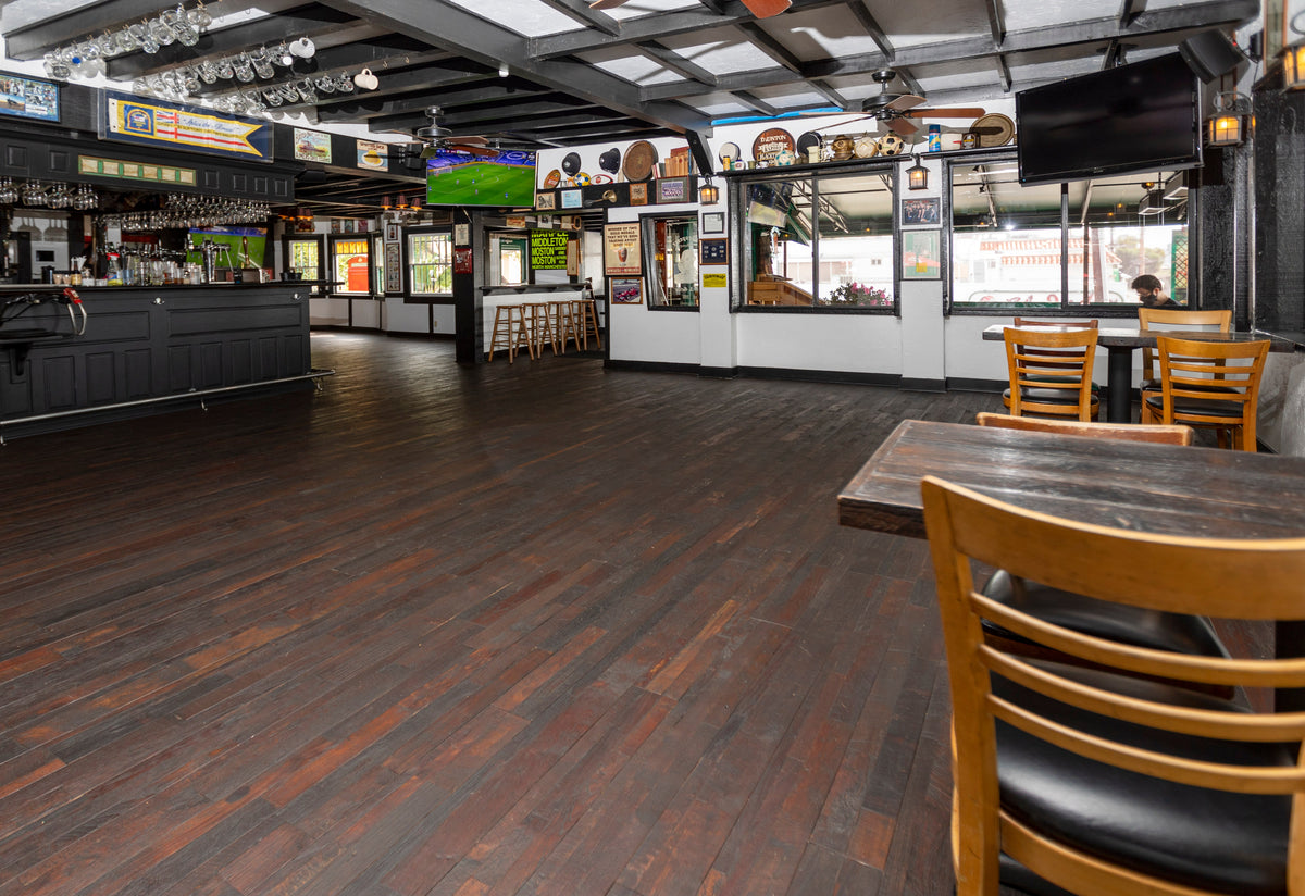 Pub room with open dark wood floor and tables along the edges