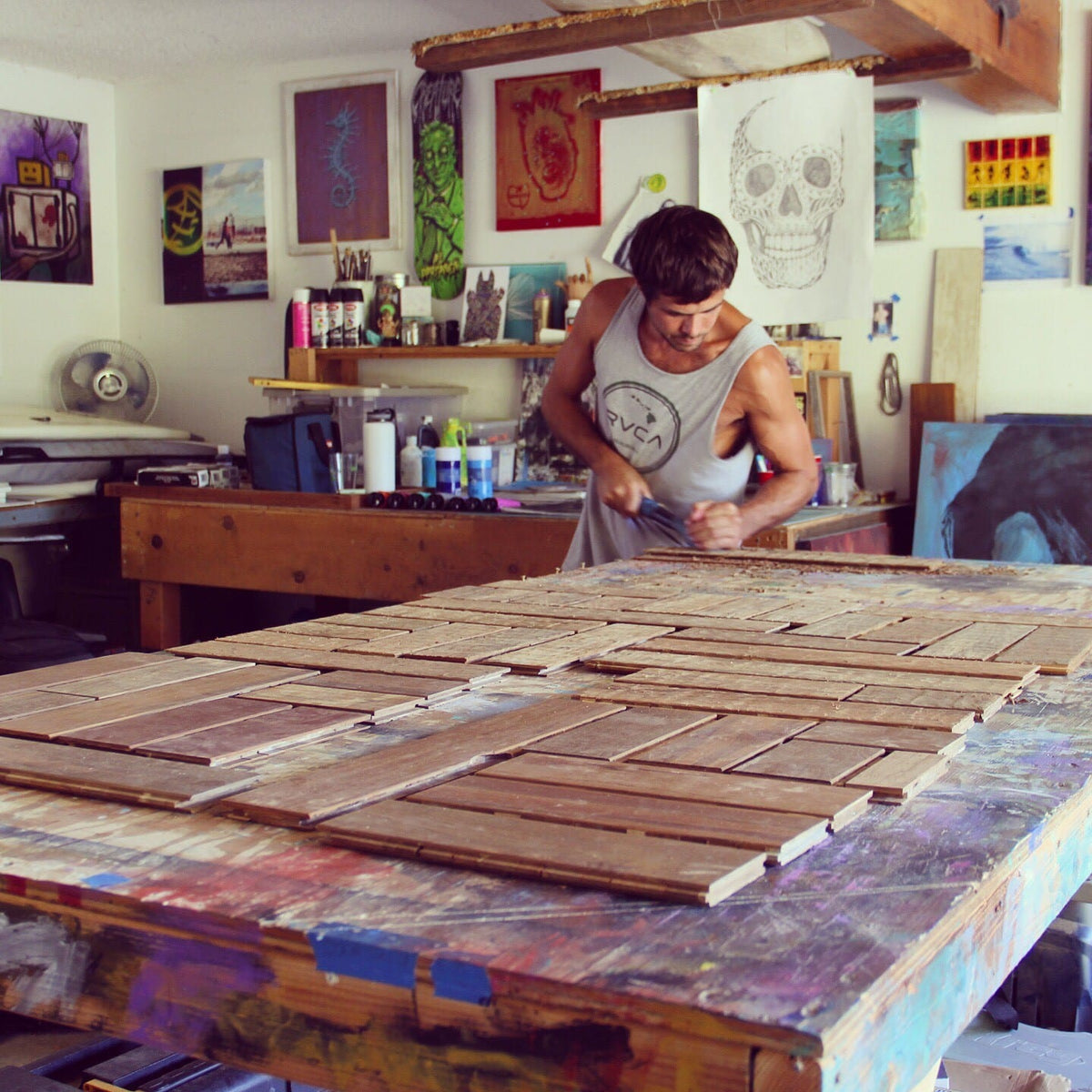 Maker working over a large wood panel on a workshop table