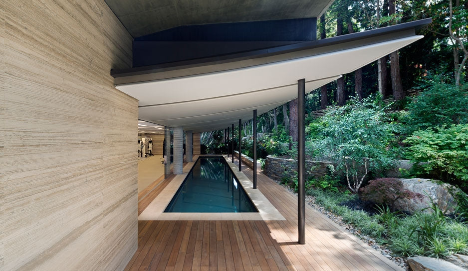 Wood decking beside a long pool and a planted hillside