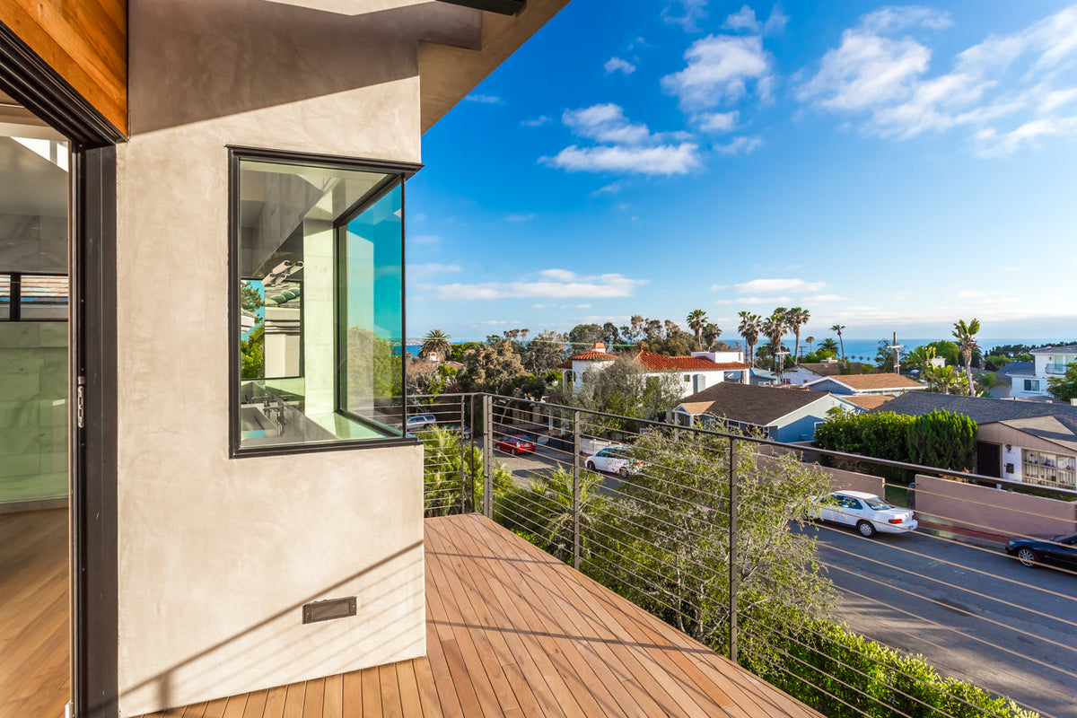 Wood deck boards meet the corner of a light-colored exterior wall