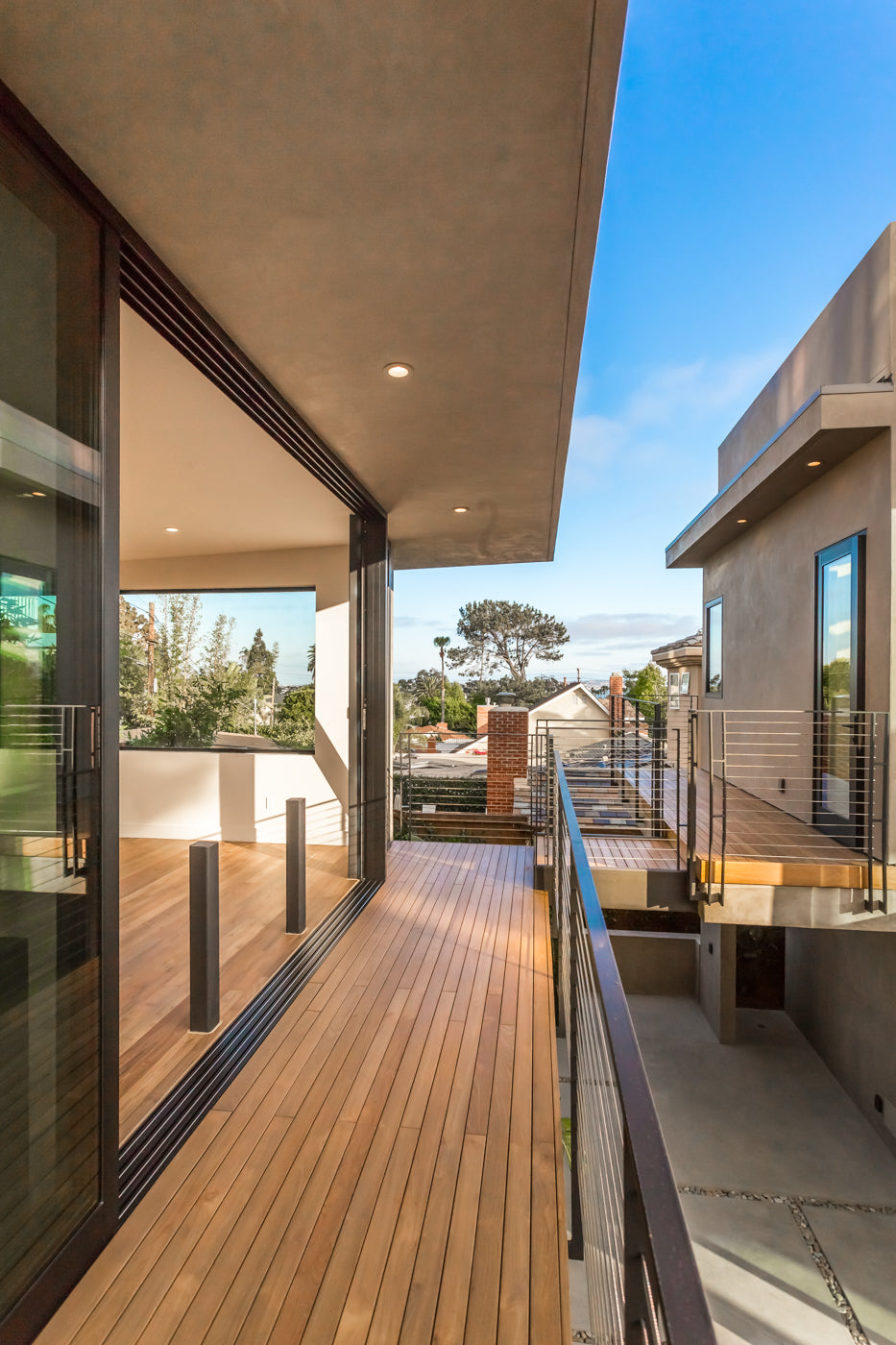 A narrow wood deck runs beneath a roof overhang beside glazed doors