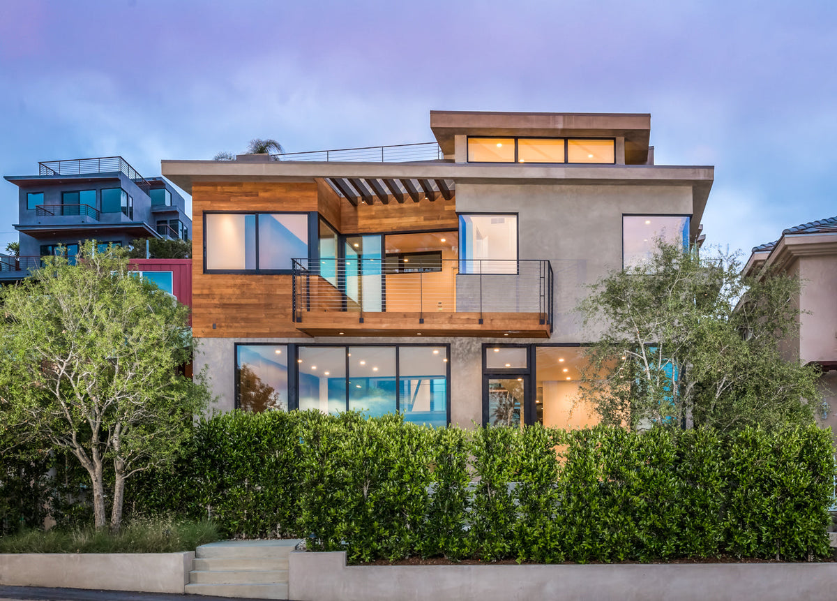 A modern house with illuminated upper-level wood terrace at dusk