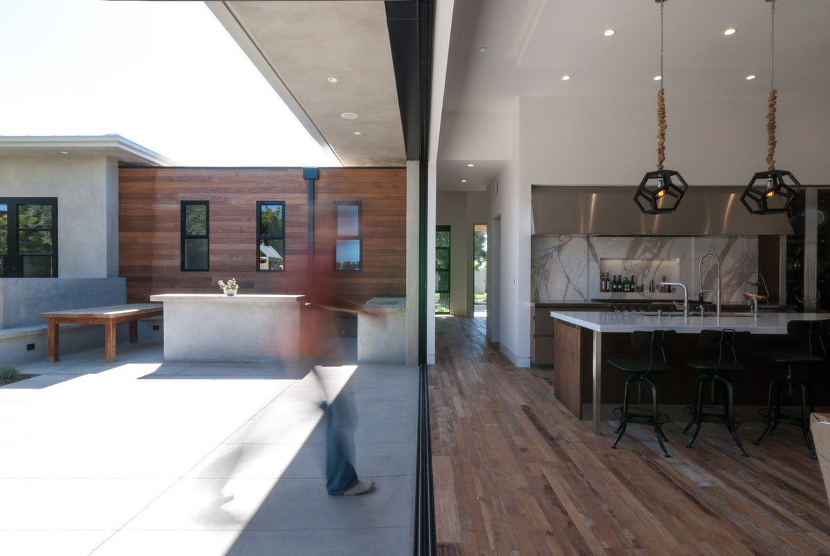 Open indoor-outdoor threshold with pale patio surface adjoining brown wood flooring