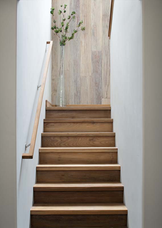 Wood stair treads between white walls with timber surface at upper landing