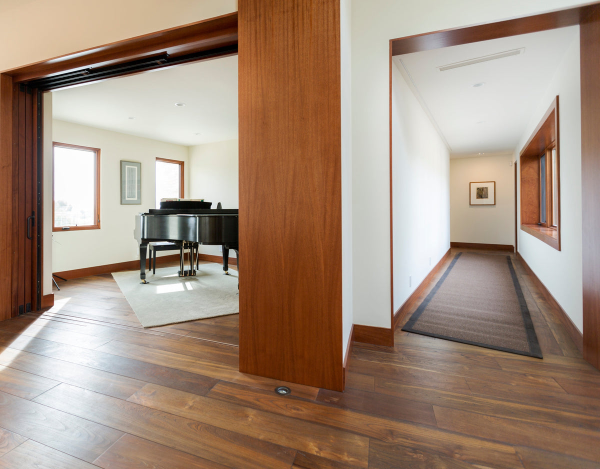 Wood doorway between a furnished room and long hall, with continuous flooring