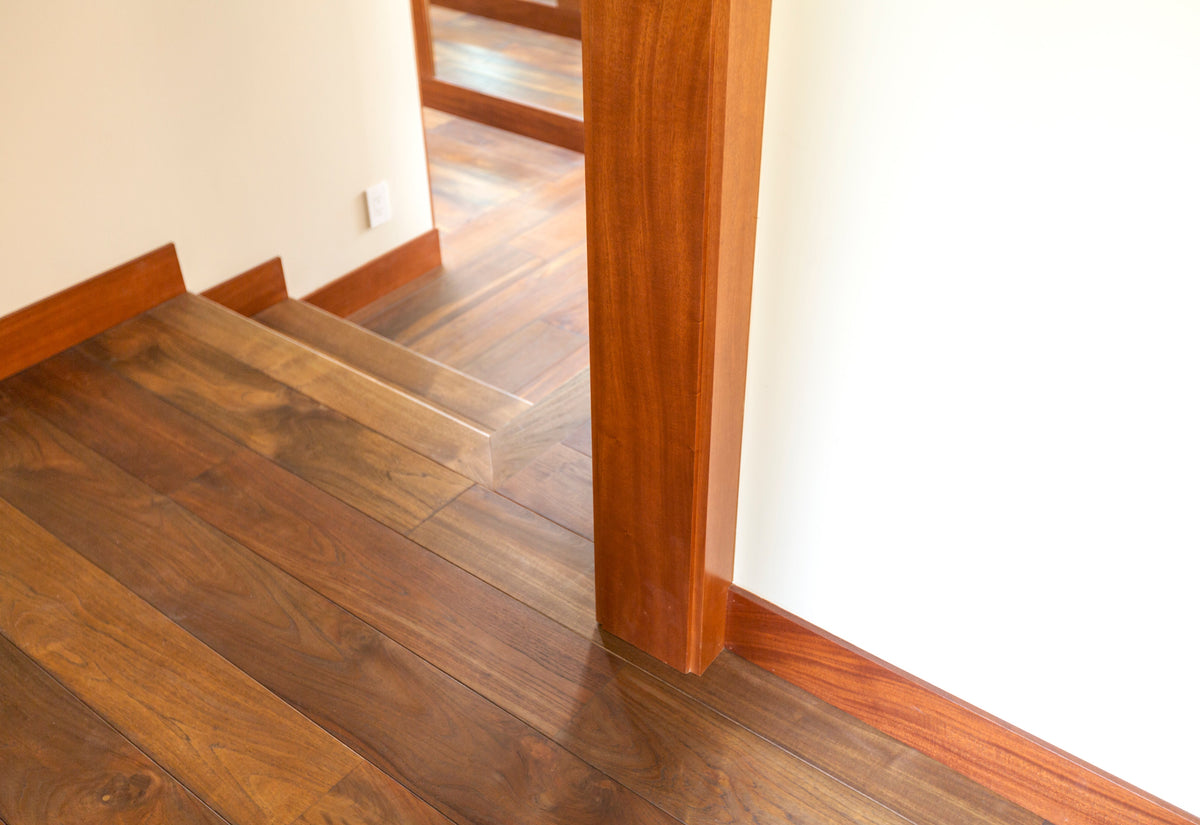 Close floor view at a doorway showing contrasting plank directions