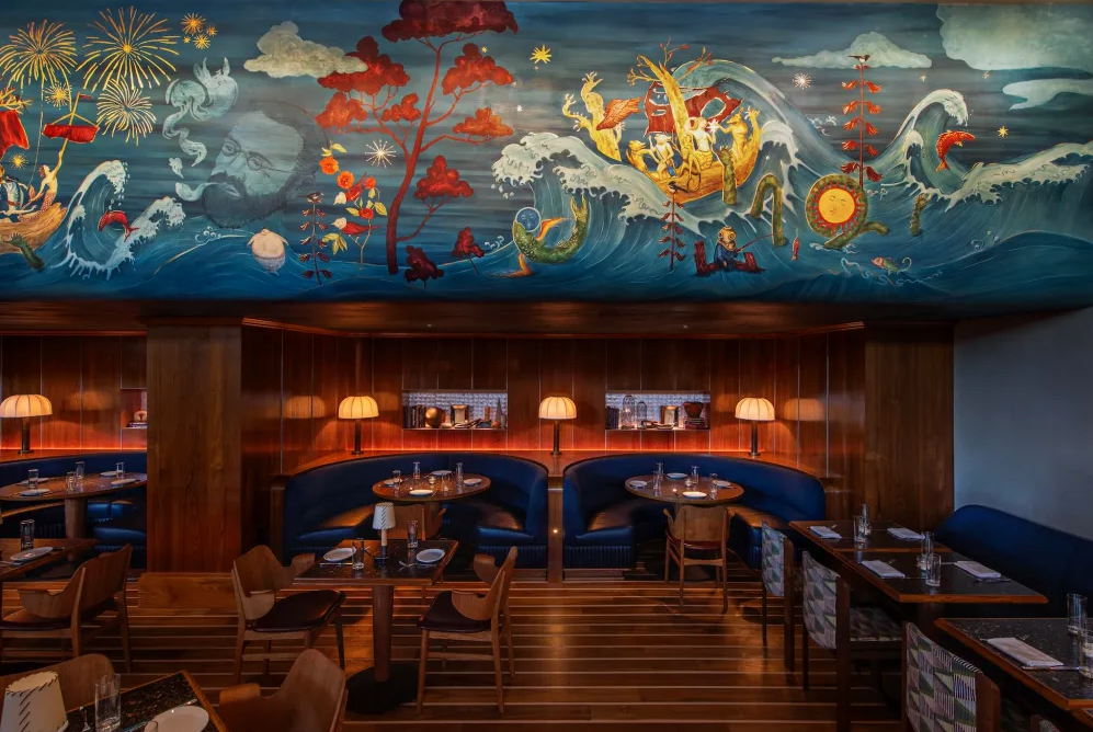 Wood-floored restaurant with pale floor stripes, curved blue booths, wood chairs and a marine mural