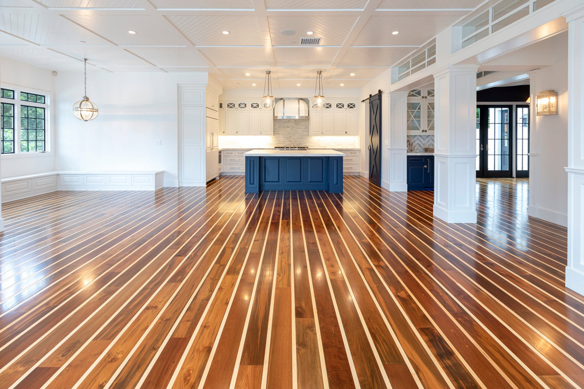 Bright open interior with a striped wood floor, white walls and a navy kitchen island