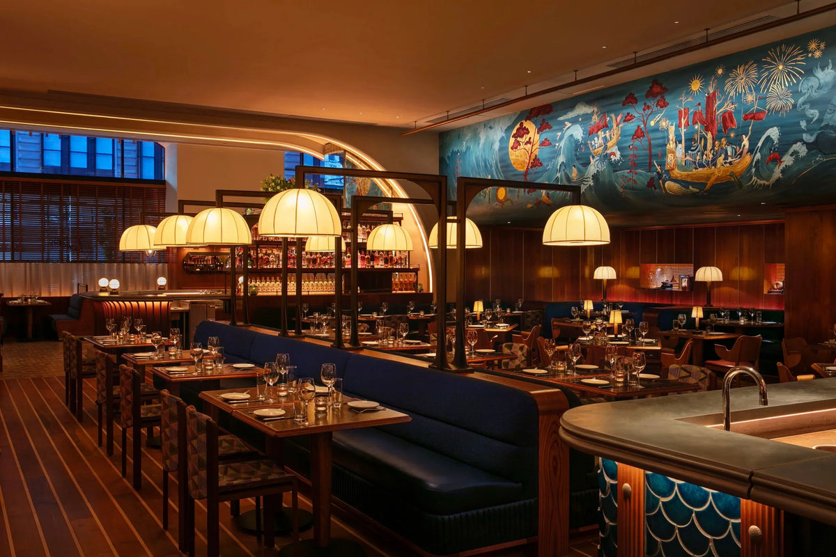 Restaurant interior with narrow pale stripes across a dark wood floor, blue seating, pendant lamps and a marine mural