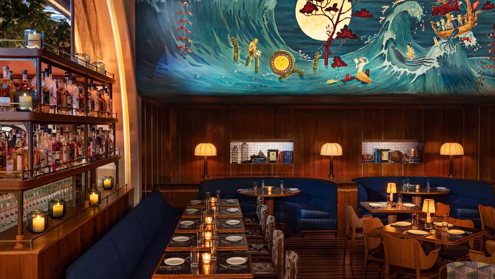Restaurant dining area with blue banquettes, a marine mural and narrow light stripes across dark wood flooring