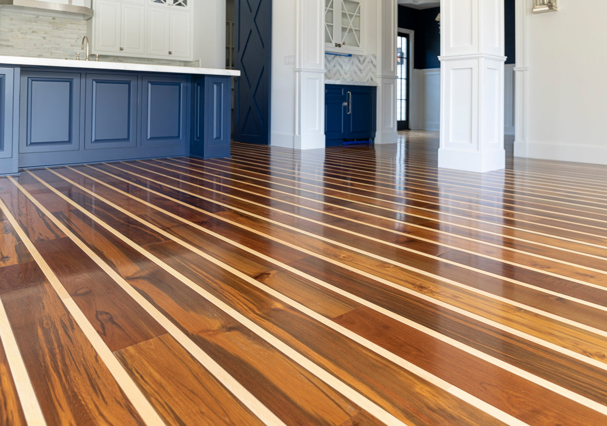 Low-angle view of dark wood floorboards with narrow pale stripes beside navy cabinets
