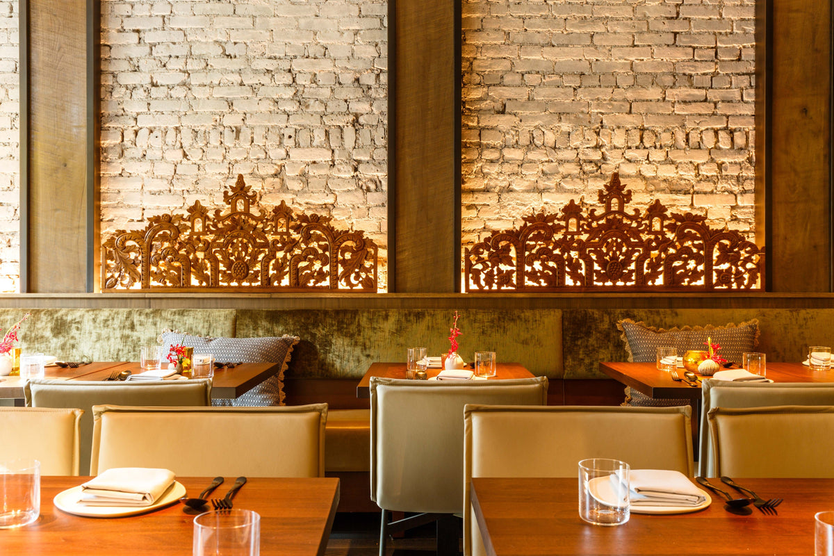 Wood restaurant tables set with white plates beside upholstered seating