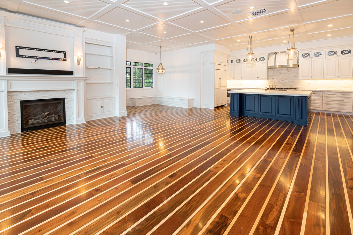 Open room with striped wood flooring connecting a fireplace and navy kitchen island
