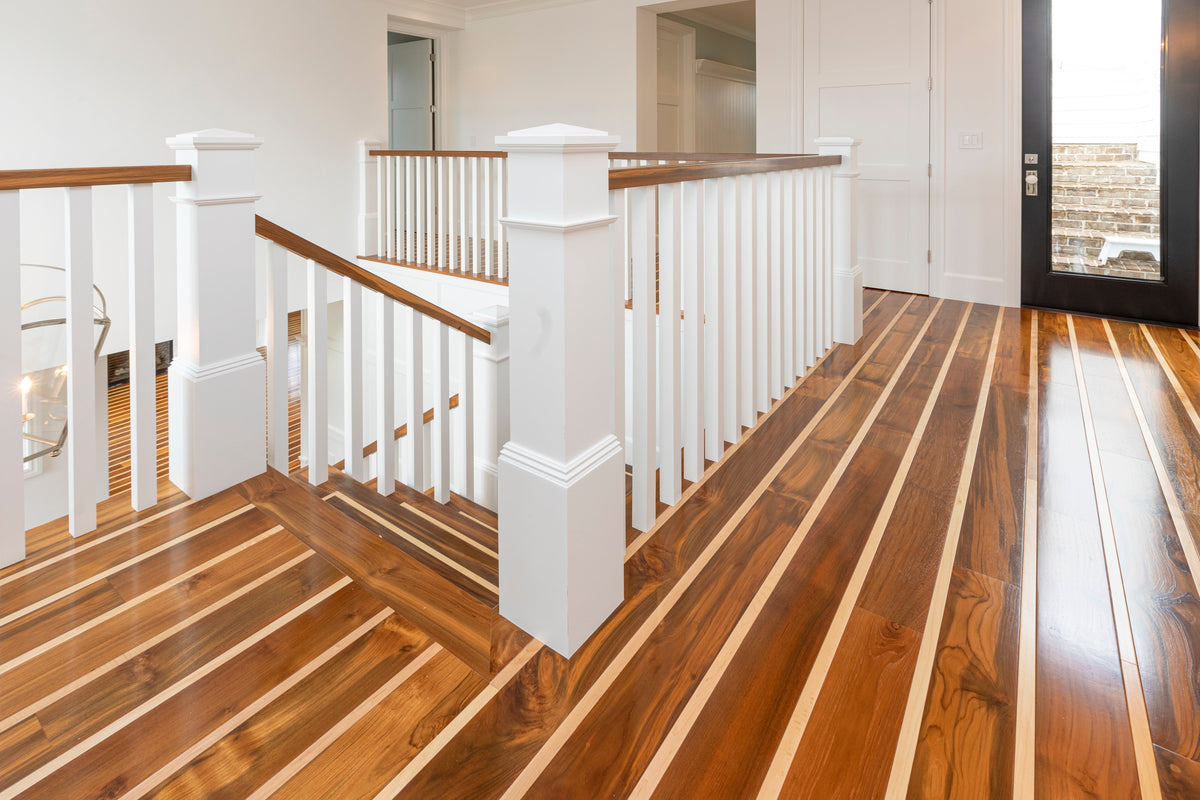 Striped wood flooring around a white stair balustrade and adjoining upper-floor doorways