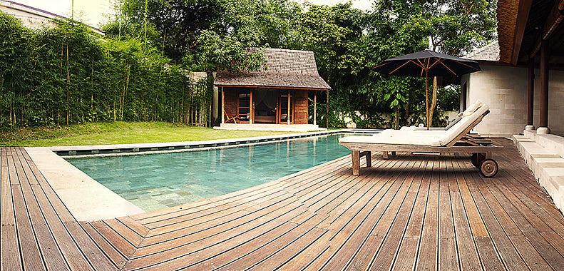 Wood deck boards form a geometric pool surround beside loungers and garden planting