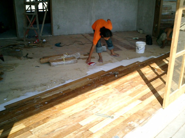 Worker positioning boards beside a partly laid wood floor
