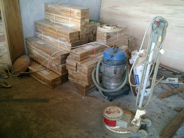 Bundled wood boards stacked beside equipment in an unfinished room