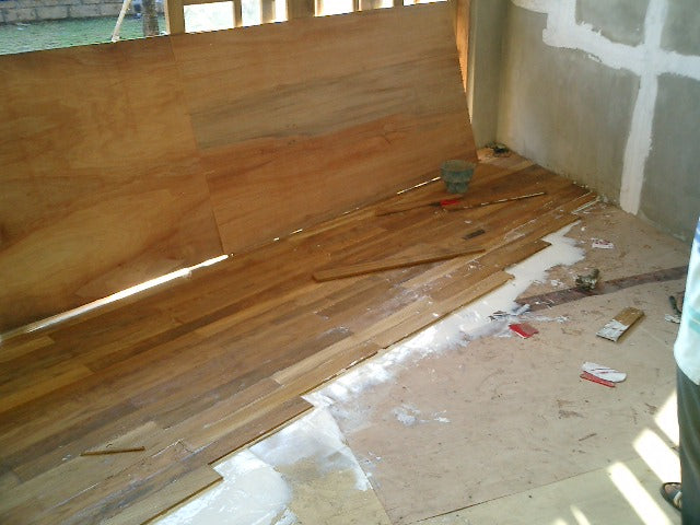 Loose and partly installed wood boards beside an unfinished wall